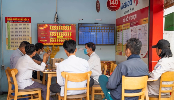Đông đảo người chơi nán lại điểm bán hàng để dò số Keno trực tiếp qua màn hình lớn. Ảnh: Vietlott
